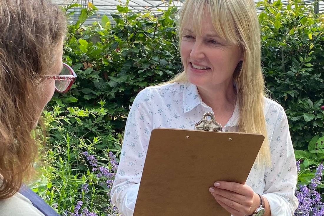 Marianne holding a clipboard, speaking with a woman, providing garden design consultation