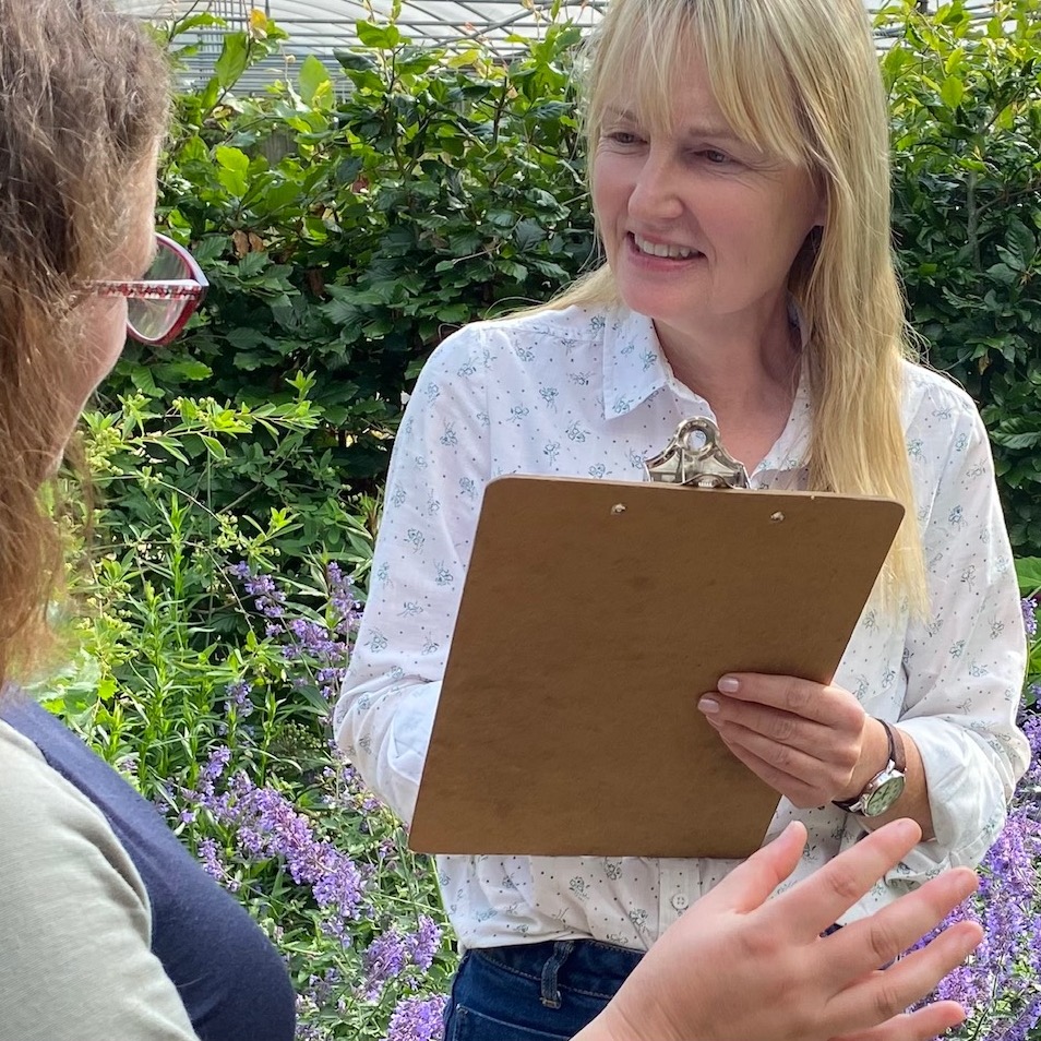 Marianne holding a clipboard, speaking with a woman, providing garden design consultation